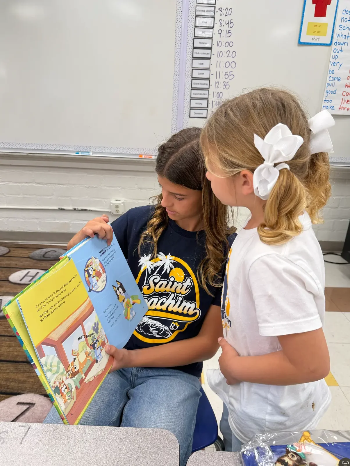 Capri reading a book with a younger girl in her school reading buddy program